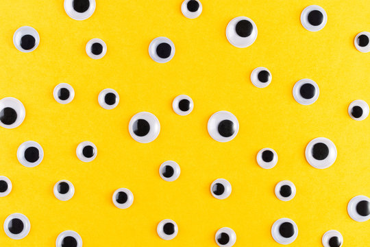 Googly plastic eyes pattern on yellow backgroud. Used for imitation of eyeballs for handcraft toys and dolls and others creativity. Flat lay.