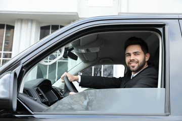 Handsome young man driving his modern car