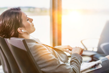 Portrait of businesswoman listening to music on smartphone while sleeping and waiting for boarding...