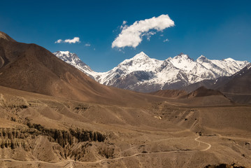 Fototapeta na wymiar A view of the snow covered peaks of the Nilgiri range from the Himalayan village of Tiri in Upper Mustang in Nepal on a sunny day.