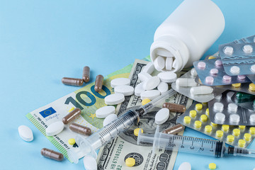 Medical pills are on a money on a blue background. Medical pills on money background as a symbol of...