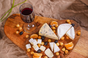 glass of wine and Assorted cheeses on wooden Board