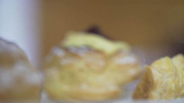 Closeup backlit of a woman getting a tasty bignè with black cherry and soft cream. Pastries. Cream puffies. Italian zeppole di San Giuseppe.