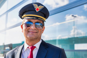 Portrait of mature confident pilot captain  wearing eyeglasses in airport © MDBPIXS