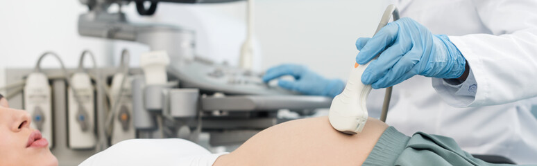 panoramic shot of professional doctor examining belly of pregnant woman with ultrasound scan - obrazy, fototapety, plakaty