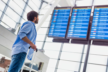 Low angle view of man looking at his flight on screen in airport