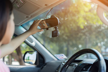 Close up of Asian female hands on adjusting rearview mirror in car while Learn to drive a car and safety on road. concept of Traveler girl on car trip, looking at the road. View over shoulder