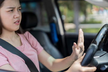 Angry and hopeless young asian female Driver Pressing Horn And Screaming at someone While Driving. concept of Car traffic at rush hour in downtown area of the city and people. Car pollution