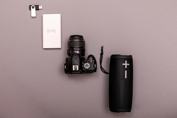 Bluetooth speaker and powerbank with dslr camera closeup on grey background. Online music concept.