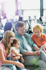 Mature man using digital tablet while his wife and daughter looking in airport
