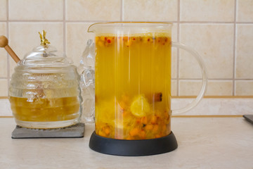 Vitamin useful sea buckthorn tea in a glass teapot with fresh sea buckthorn berries, orange, cinnamon sticks and honey. The concept of rest, relaxation. top view with a copy of the space