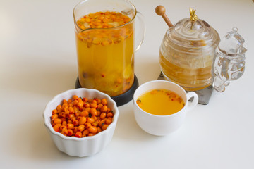 Vitamin useful sea buckthorn tea in a glass teapot with fresh sea buckthorn berries, orange, cinnamon sticks and honey. The concept of rest, relaxation. top view with a copy of the space