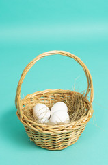 Fototapeta na wymiar Easter holiday: a small basket with white eggs on a blue background.