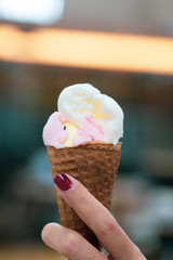 A girl holds ice cream cones with strawberry and vanilla