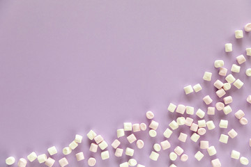 Background or texture of pink and white mini marshmallows on purple background with free space for text