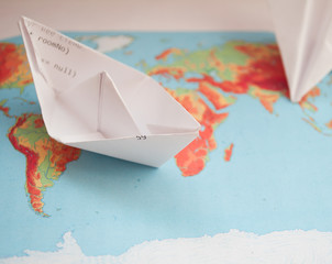 Paper boat and paper plane on a world map, fly or sail abroad, sea tourism, flights, tourism day