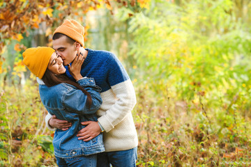 Naklejka na ściany i meble Stylish fashion couple kissing outdoors in autumn. First kiss. Sensual young couple walking in autumn park. Romantic first date.