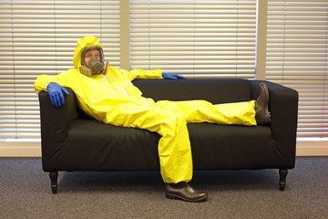 Quarantine - home arrest -  professional in protective clothing, lying  on the sofa and doing nothing - obrazy, fototapety, plakaty