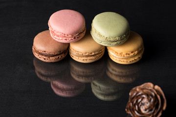 colored macarons on a black surface and with a reflection