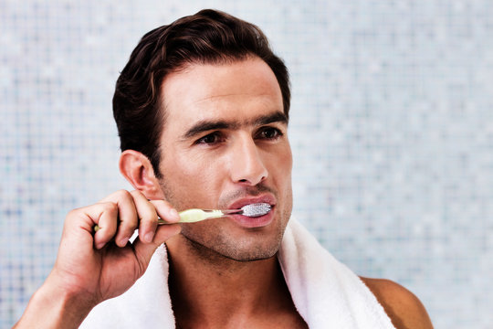Portrait of man brushing his teeth while looking in to the mirror
