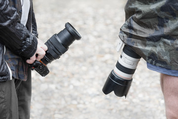 two photographers are standing opposite each other in their hands cameras with a zoom lens