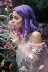 Little fairy with purple hair harm the pink flowers 