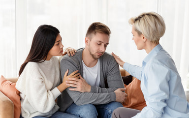 Naklejka na ściany i meble Wife And Psychologist Comforting Addicted Husband At Psychotherapy Session Indoor