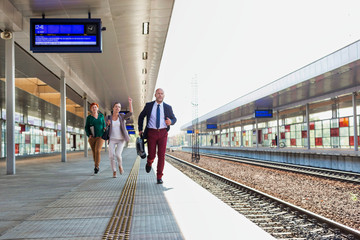 Portrait of business people running to catch the train in station