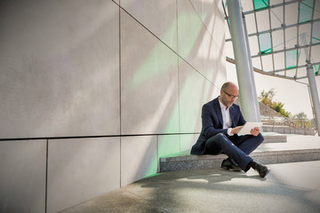 Portrait of businessman using digital tablet while sitting outside the office