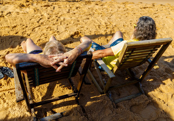 couple of husband and wife adults, Europeans lie in beach sunbeds on the sandy ocean shore in Asia, Sri Lanka
