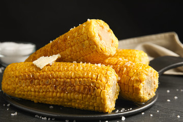 Delicious grilled corn with butter on table, closeup