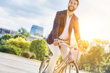 Portrait of young attractive businessman riding bicycle - obrazy, fototapety, plakaty