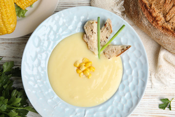 Delicious corn cream soup served on white wooden table, flat lay