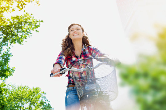 Portrait of young beautiful woman smiling while riding bicycle in the middle of the city
