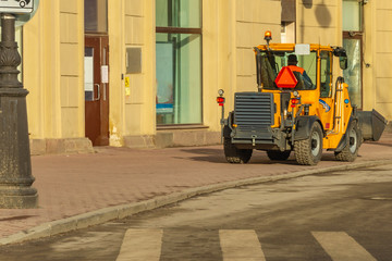 Mini excavator for cleaning city streets on the sidewalk.