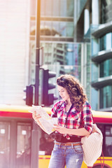 Portrait of young attractive woman looking on the map in the city with lens flare in background