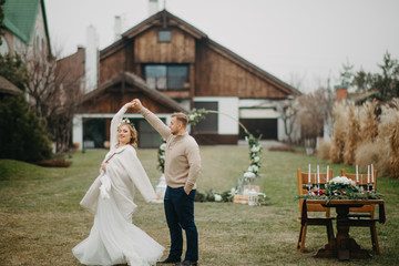 Newlyweds dance near banquet table and wedding arch.