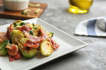 Delicious roasted Brussels sprouts with bacon served on grey table, closeup