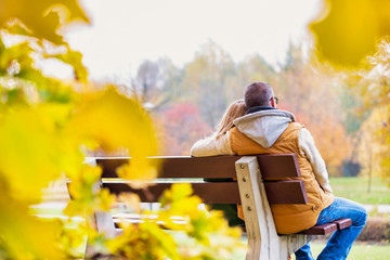 Portrait of mature couple sitting on bench while enjoying autumn in park