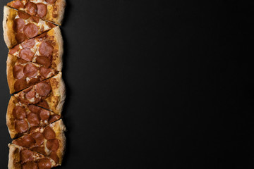 Food ingredients and spices for cooking mushrooms, tomatoes, cheese, onion, oil, pepper, salt, basil, olive and delicious italian pizza on black concrete background. Copyspace. Top view. Banner
