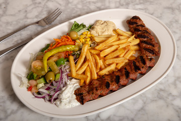 Turkish food dish. Adana kebab with hummus chips and salad.
