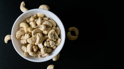 superfood, cashew nuts in a white plate on a black background top view