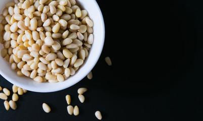 superfood, pine nuts in a white plate on a black background top view