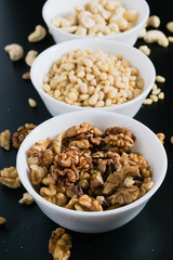 superfood concept, cedar, walnuts, cashew nuts in a plate on a black background