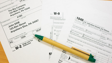 United States federal income tax return IRS 1040, W-2 and W-9 documents and Green Pen. Wage and tax statement concept