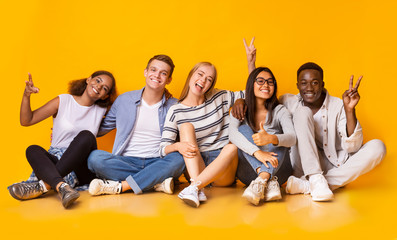 Carefree teenagers having fun over yellow studio background