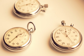 Three retro mechanical stopwatches on a light background.
