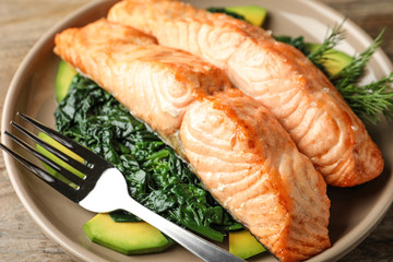 Tasty salmon with spinach and avocado on table, closeup