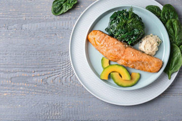 Tasty salmon with spinach and avocado on grey wooden table, flat lay. Space for text
