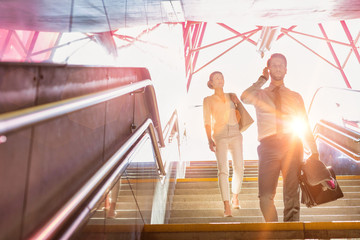 Business people walking downstairs with lens flare in background